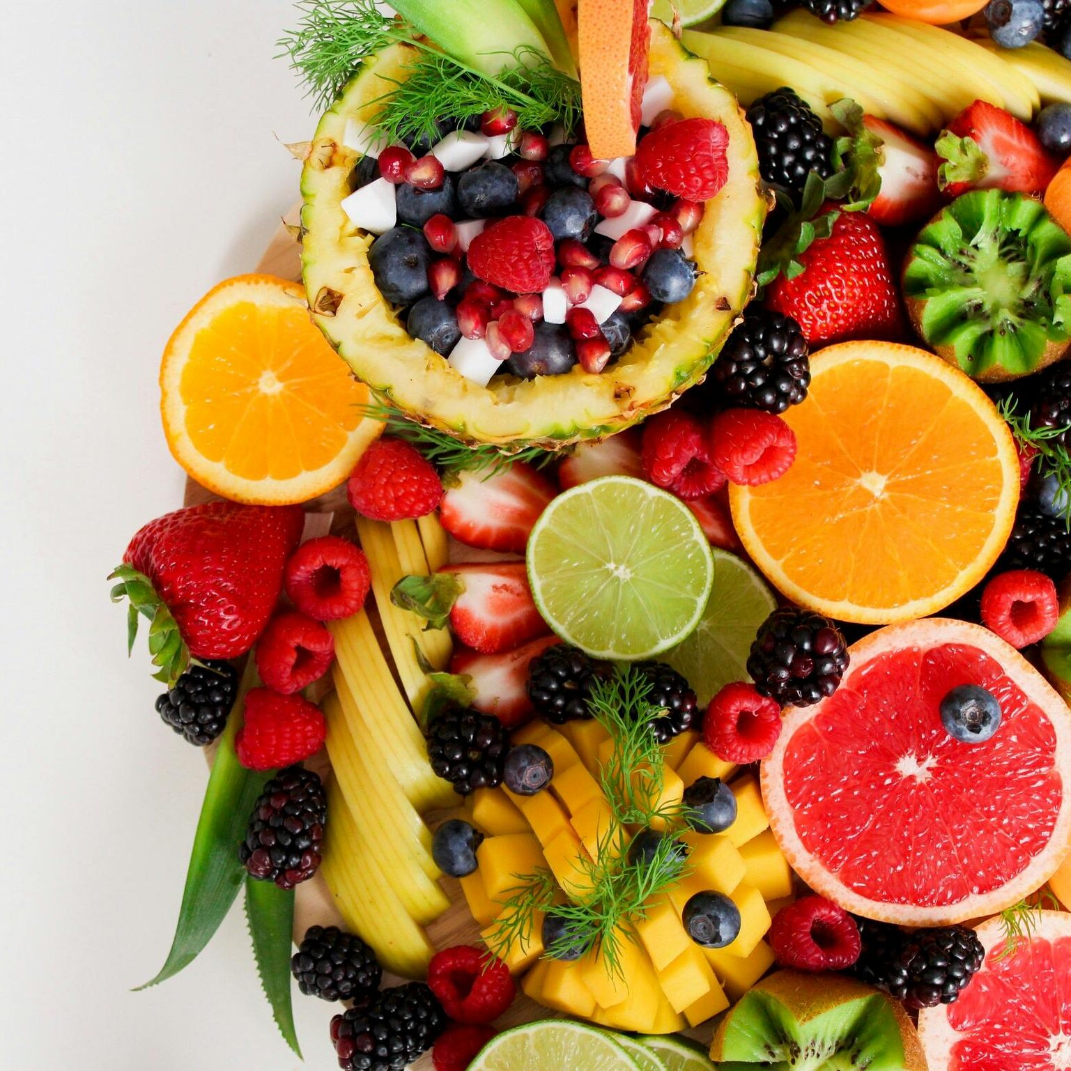 Colorful flat lay of assorted tropical fruits including pineapple, berries, and citrus.
