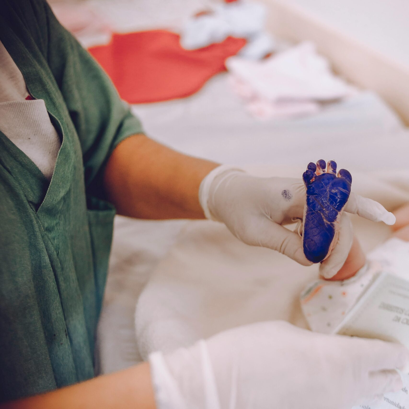 Medical professional taking footprint of a newborn baby in hospital setting.