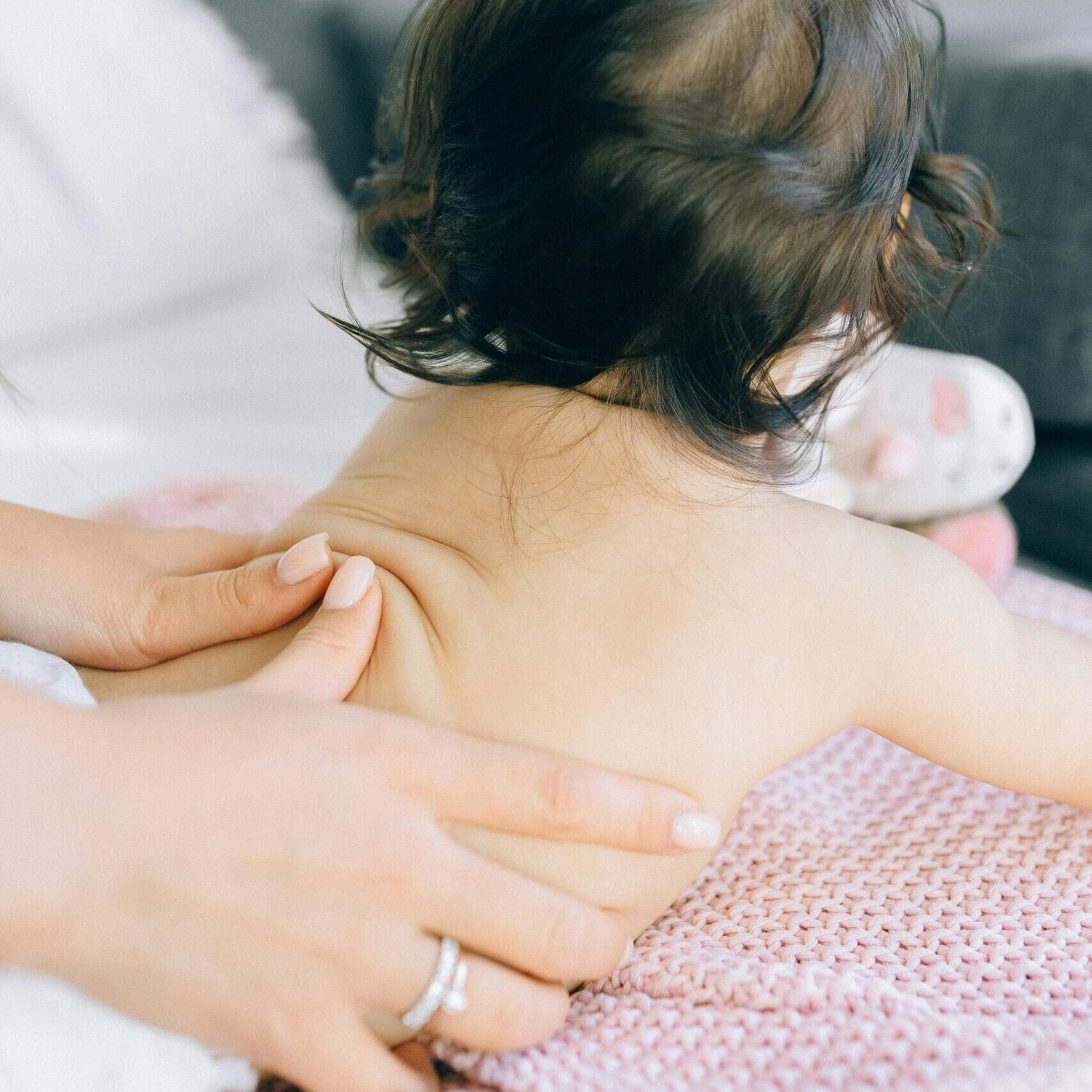A gentle massage being given to a baby on a soft blanket, promoting relaxation.