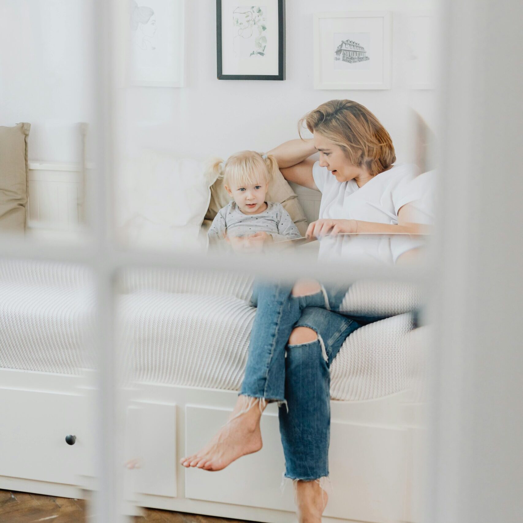 A loving mother and daughter share a tender moment sitting together in a cozy, white-walled room.