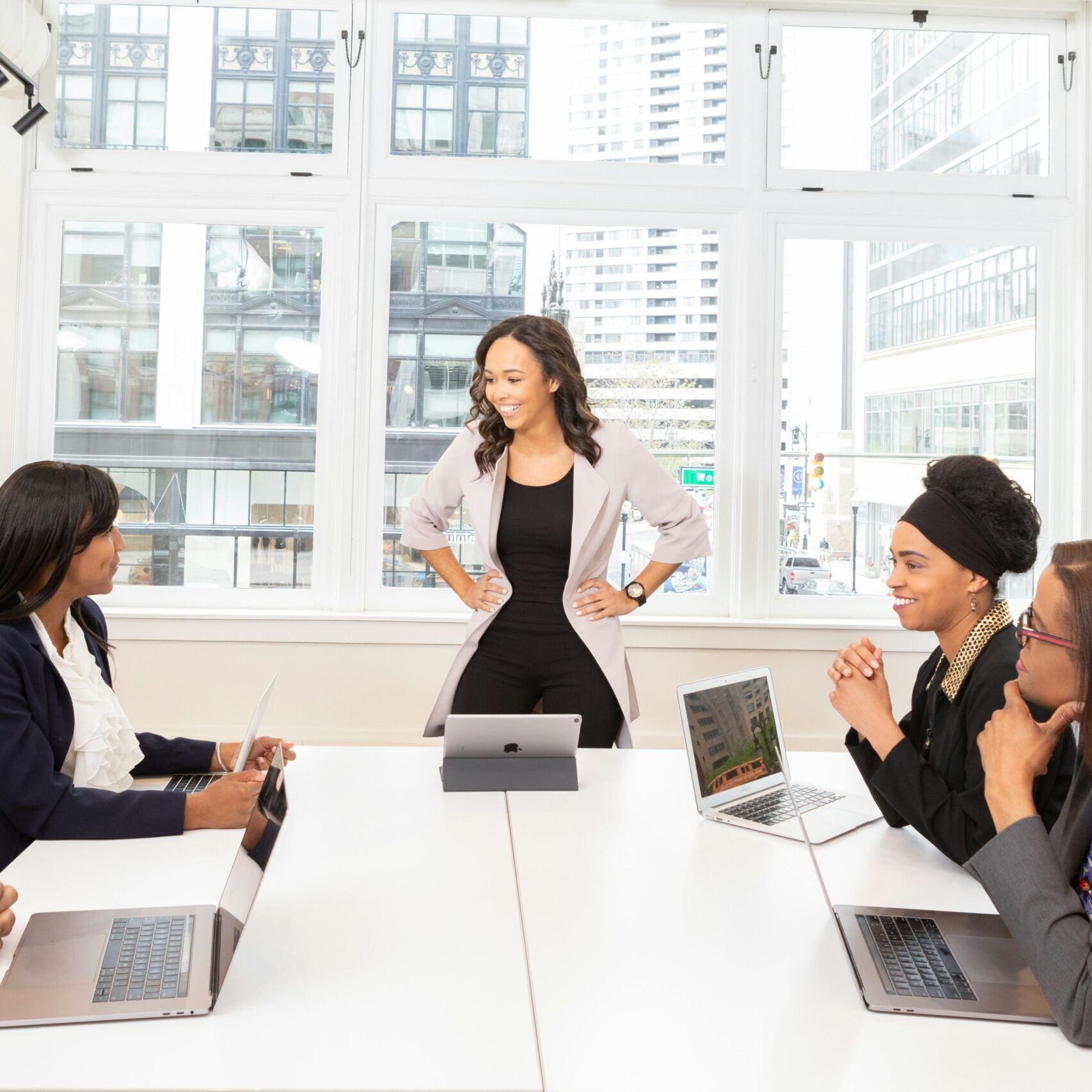 Diverse team engaged in a business meeting with laptops in a modern office setting.