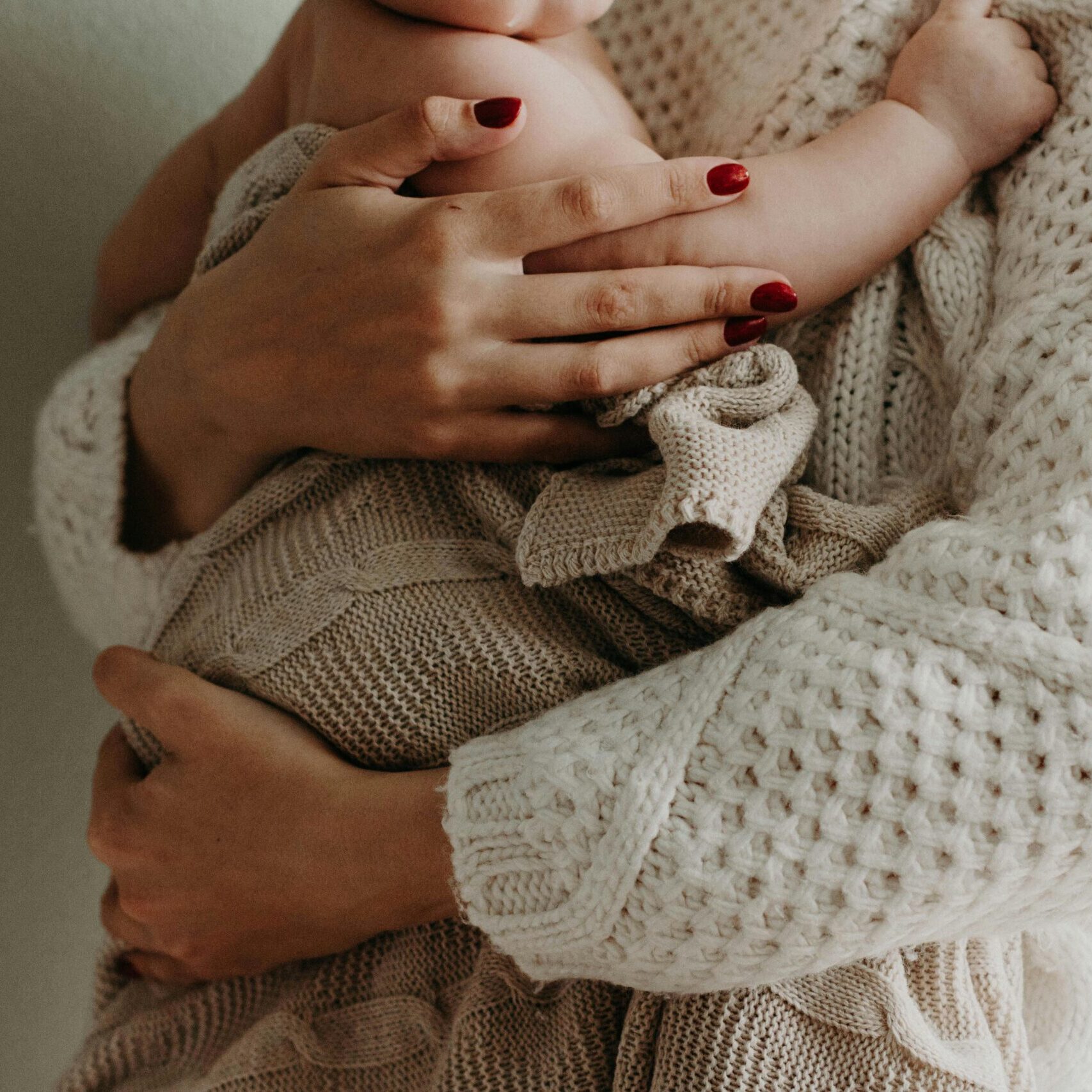 Close-up of a mother holding her baby in warm knitwear, conveying love and togetherness.
