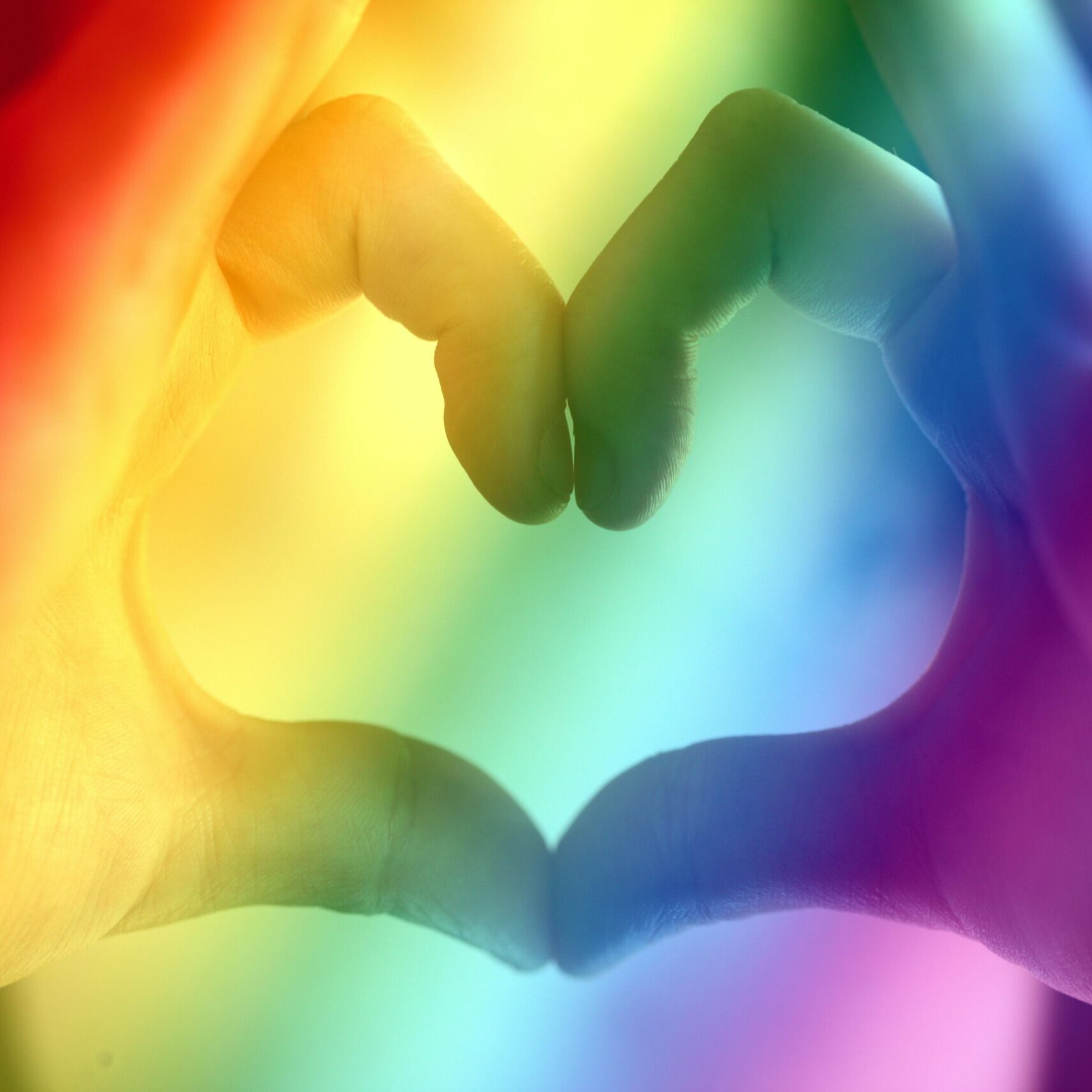 Hands forming a rainbow heart shape, symbolizing love, unity, and LGBTQ pride.
