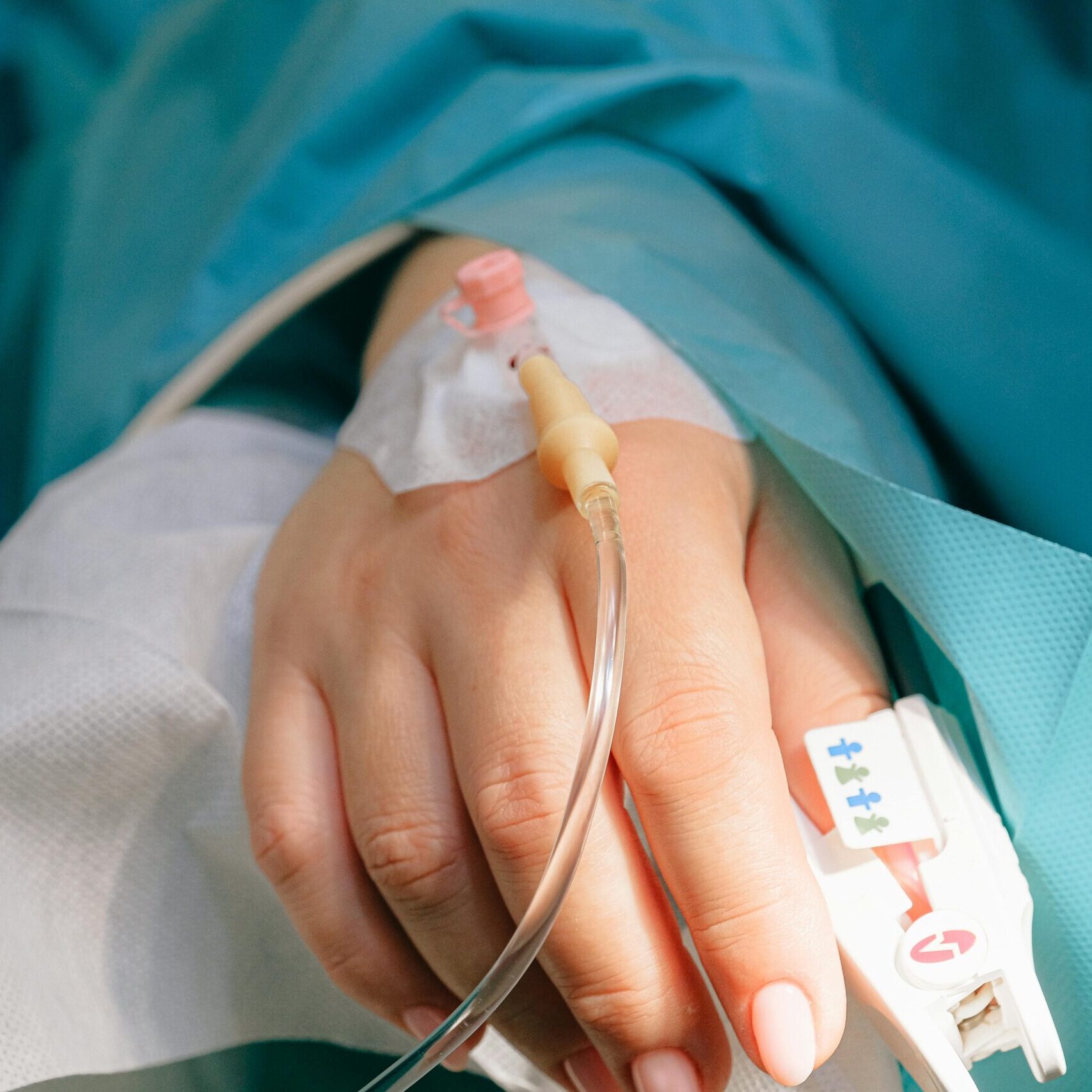 Close-up of a patient's hand with intravenous therapy and pulse oximeter, symbolizing healthcare and treatment.