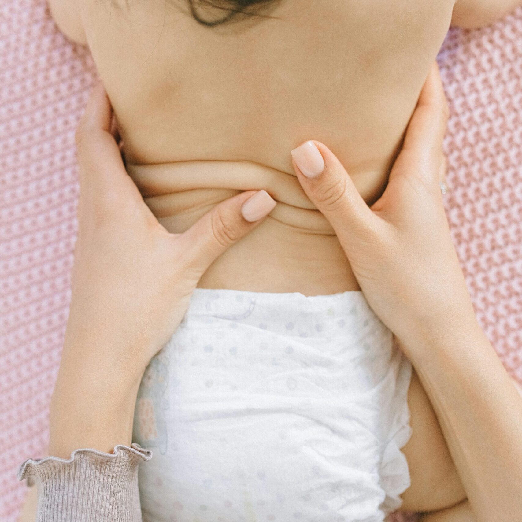 A soothing massage for a baby on a soft pink blanket, enhancing relaxation.