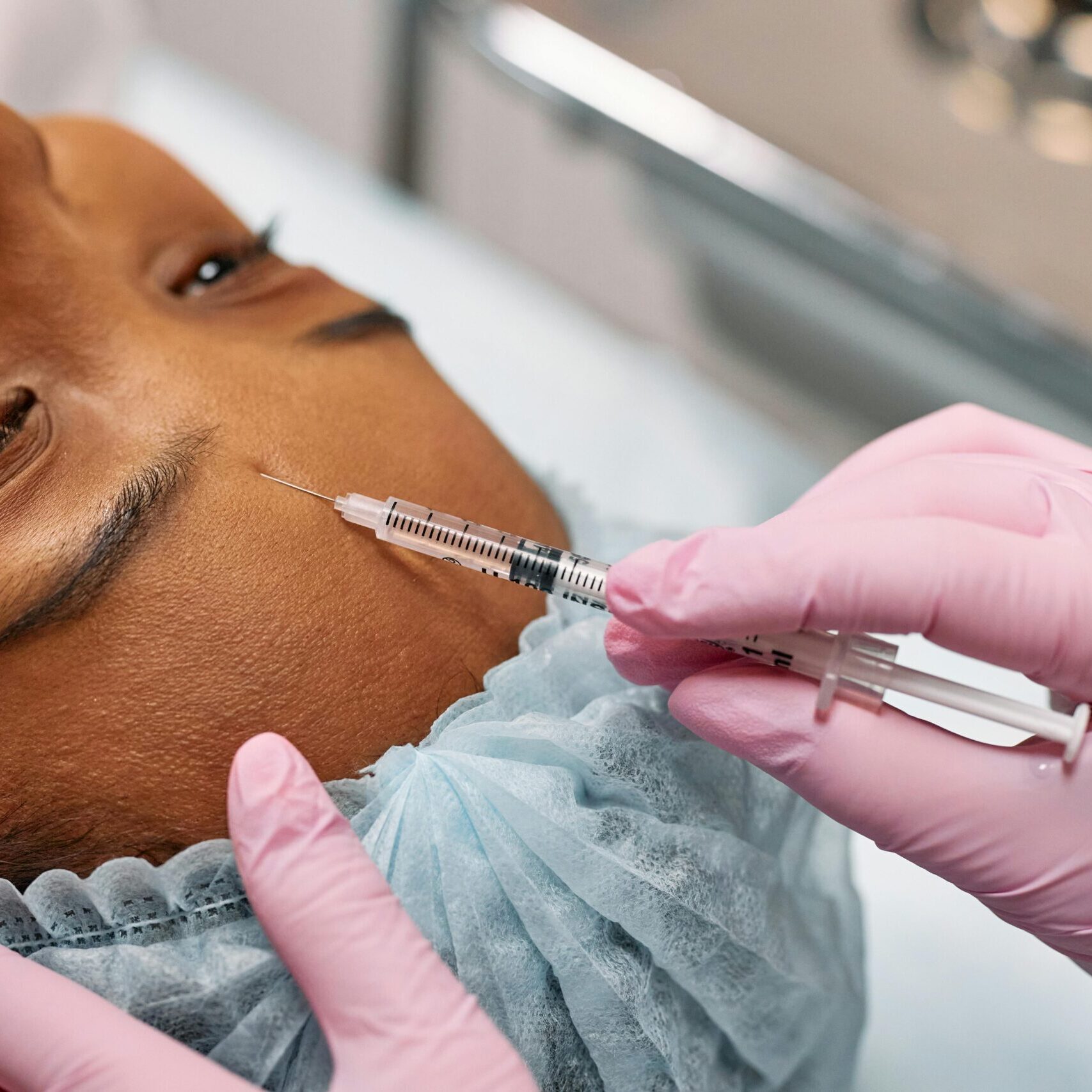 Close-up of a woman receiving a cosmetic injection on her forehead in a clinical setting.
