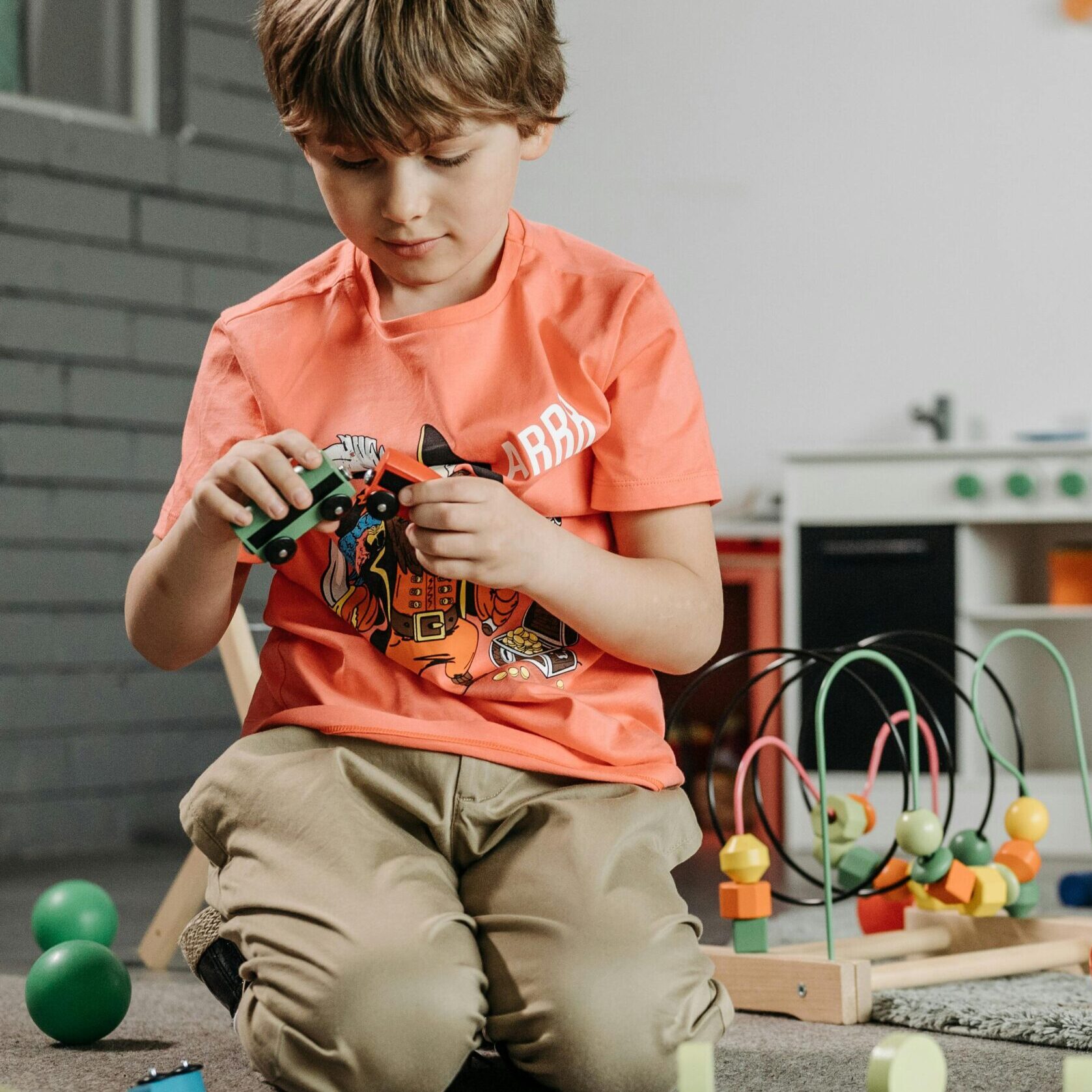 Child playing with colorful toys in a cozy indoor playroom setting.